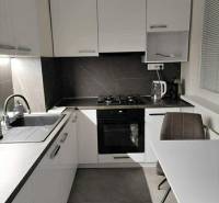 Küche mit weißen Schränken und einem Tisch in einer Zweizimmerwohnung mit Holzboden.