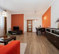Wohnzimmer mit einer orangefarbenen Wand, einem Boden in Holzoptik und einem roten Sofa in einer Zweizimmerwohnung.