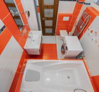 Badezimmer einer Zweizimmerwohnung mit auffälligen orange-weißen Fliesen und Sanitärtechnik.