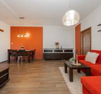 Wohnzimmer in einer 2-Zimmer-Wohnung, orangefarbene Wand, rotes Sofa, Boden mit Holzdekor.