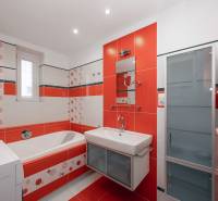 Badezimmer in einer 2-Zimmer-Wohnung mit orange-weißen Fliesen und einer Badewanne.