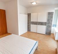 Schlafzimmer mit Bett, Kleiderschrank und Holzboden in einer Zweizimmerwohnung.