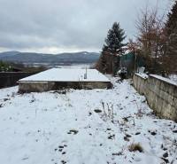 Verschneite Erholungsgrundstücke in Považská Bystrica mit Blick auf die Berge und gepflanzten Bäumen.