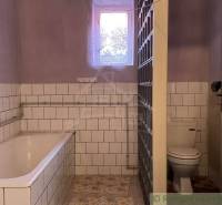 Badezimmer in einem Einfamilienhaus mit Badewanne, Toilette und Fensterglas.