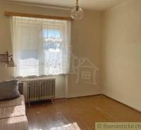 Ein Zimmer in einem Einfamilienhaus mit einem Sofa, einem Fenster und einem Boden mit Holzdekor.