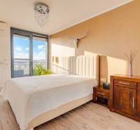 Schlafzimmer in einer 3-Zimmer-Wohnung mit Bett, Kommode, Dekorationen und Boden mit Holzdekor.