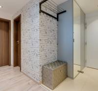 Flur mit Holzboden, weißer Wand und glänzender Bank in einer 3-Zimmer-Wohnung.