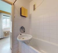 Badezimmer mit Badewanne und weißen Fliesen in einer 2-Zimmer-Wohnung.