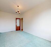 Ein Zimmer in einer 2-Zimmer-Wohnung mit Teppich und gemustertem Vorhang.