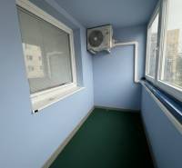 Veranda mit Verglasung und Klimaanlage in einer 2-Zimmer-Wohnung, ausgestattet mit Jalousien und grünem Teppich.