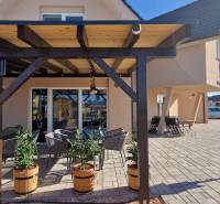 Gastroräume in Nová Dedinka mit Pergola, Blumenkästen und Außensitzbereich auf Pflastersteinen.