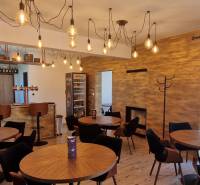 Gasträume mit hängenden Lichtern, Holzelementen und gemütlichen Sitzgelegenheiten.