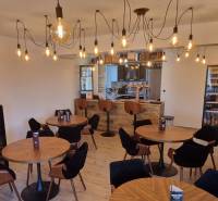 Innenraum von Gastronomiebereichen mit Holzboden und Glühbirnenbeleuchtung.