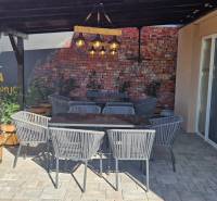 In den Außenbereichen der Gastronomie in Nová Dedinka gibt es Rattan-Stühle und eine Ziegelwand.