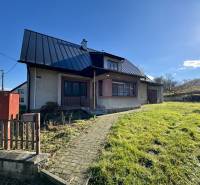 Ein Einfamilienhaus in Šarišské Čierne mit Rasen, Schrägdach und Garten.
