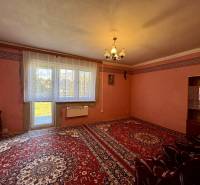 Wohnzimmer in einem Einfamilienhaus mit rotem Teppich, schlichten Vorhängen und Licht.