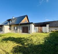 Ein Einfamilienhaus in Šarišské Čierne mit Rasen, modernem Dach und teilweise hölzernen Wänden.