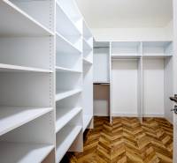 Ein Kleiderschrank mit weißen Regalen und einem Boden in Holzoptik im Ferienapartment.