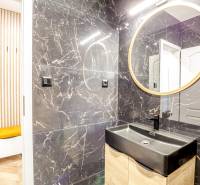 Badezimmer in der Ferienwohnung mit schwarzem Waschbecken und rundem Spiegel.