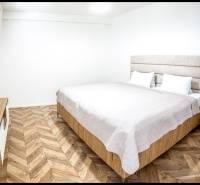 Schlafzimmer in einer Ferienwohnung mit Bett und Boden in Holzoptik.