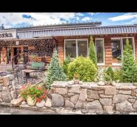 Steinfassade des Ferienapartments in Štrba mit Terrasse und Blumenschmuck.