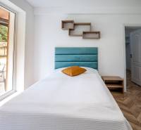 Einzelbett im Ferienapartment mit Holzboden und großem Fenster.