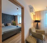 Eine Zweizimmerwohnung mit Holzboden umfasst ein Schlafzimmer, einen Sessel und eine Lampe.