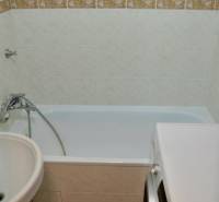 Badezimmer mit Badewanne, Waschmaschine und weißen Fliesen in einer 2-Zimmer-Wohnung.