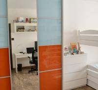 Kinderzimmer mit Etagenbett, buntem Schrank und Boden in Holzoptik.