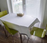 Esszimmer mit offenem Fenster, zwei Stühlen und Holzboden in einer Zweizimmerwohnung.