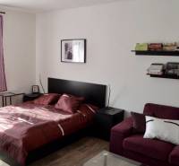 Schlafzimmer in einer 2-Zimmer-Wohnung mit Bett, Sofa und Schuhregalen.