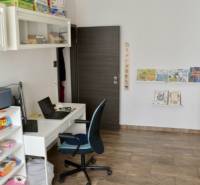 Kinderzimmer mit Tisch, Stuhl, Spielzeug und einem Boden mit Holzdekor in einer 2-Zimmer-Wohnung.