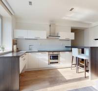 Die Küche in einer 2-Zimmer-Wohnung mit weißen Schränken und einem Boden in Holzoptik.