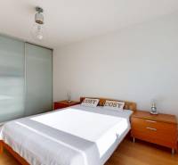 Helles Schlafzimmer mit Doppelbett, Kleiderschrank und Holzboden in einer 2-Zimmer-Wohnung.