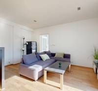 Wohnzimmer mit violettem Sofa, Fernseher und Holzboden in einer Zweizimmerwohnung.