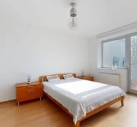 Schlafzimmer in einer 2-Zimmer-Wohnung mit einem Doppelbett, Holzschränken, großem Fenster.