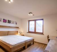 Ein Schlafzimmer in einem Einfamilienhaus mit Bett, Nachttischlampen und einem Boden in Holzoptik.