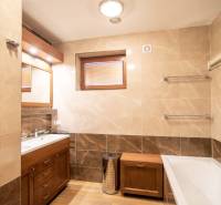 Badezimmer in einem Einfamilienhaus mit Badewanne, Waschbecken, Duschkabine und Boden mit Holzdekor.