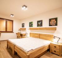 Schlafzimmer in einem Einfamilienhaus mit Holzboden, Bildern und Arbeitstischen.