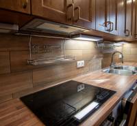 Eine Küche in einem Einfamilienhaus mit einem Boden in Holzoptik und einer Küchenzeile aus Holz.