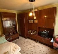 Ein Zimmer in einem Einfamilienhaus mit Möbeln, einem Bett und gemusterten Tapeten an den Wänden.