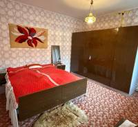 Schlafzimmer im Einfamilienhaus mit Teppich, gemusterten Tapeten und großem Schrank.