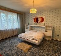 Ein Schlafzimmer in einem Einfamilienhaus mit einem Blumenmusterteppich und einem großen Fenster.