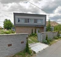 Ein Einfamilienhaus in Bystrička mit einem gepflegten Garten und einem hohen Zaun entlang der Straße.