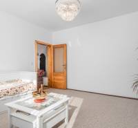 Helles Zimmer mit Blumenbettwäsche, Tisch und Kronleuchter in einer Vierzimmerwohnung.