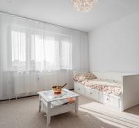 Helles Zimmer in einer 4-Zimmer-Wohnung mit Sofa, Tisch und Vorhängen am Fenster.