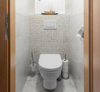 Toilette in einer 4-Zimmer-Wohnung mit gefliesten Wänden und Stauraum.