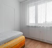 Helles Zimmer mit Bett und Fenster mit Vorhängen in einer 4-Zimmer-Wohnung.