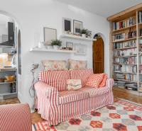 Wohnzimmer in einer 4-Zimmer-Wohnung mit gemustertem Sofa, Regal und Bücherregal.