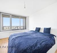 Schlafzimmer in einer 2-Zimmer-Wohnung mit Bett und großem Fenster, Boden mit Holzdekor.